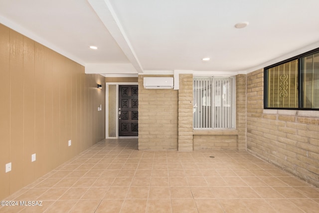 tiled spare room featuring wood walls, a wall mounted AC, and brick wall