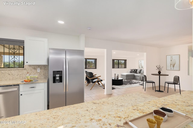 kitchen with decorative backsplash, appliances with stainless steel finishes, light tile patterned floors, and white cabinetry