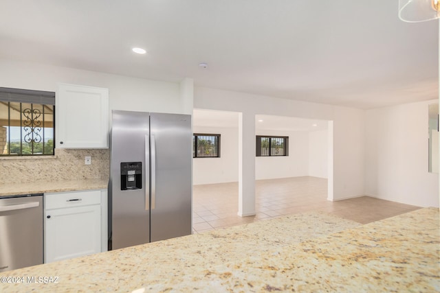 kitchen featuring stainless steel appliances, decorative backsplash, light tile patterned floors, and white cabinetry