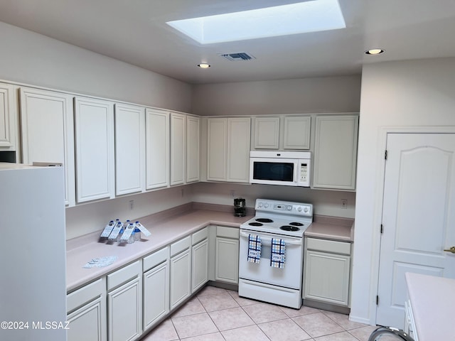 kitchen featuring light tile patterned floors, white appliances, a skylight, visible vents, and light countertops