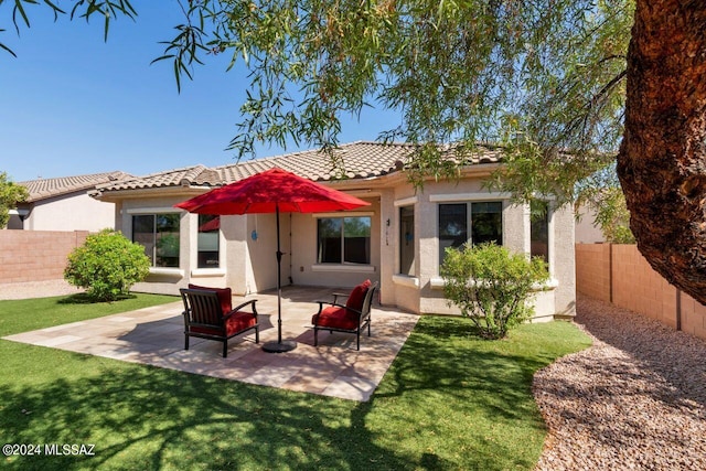 rear view of property with a patio and a lawn