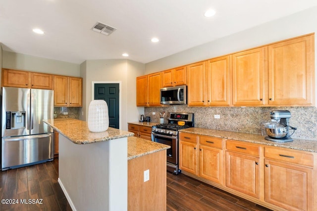 kitchen with light stone counters, dark hardwood / wood-style flooring, stainless steel appliances, and a center island