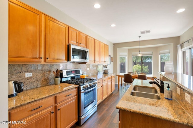 kitchen featuring light stone countertops, appliances with stainless steel finishes, sink, and decorative light fixtures