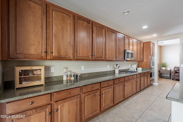 kitchen featuring dark stone countertops, light tile patterned floors, and appliances with stainless steel finishes