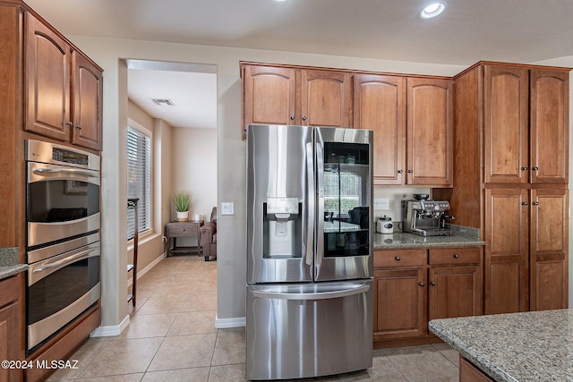 kitchen featuring light stone counters, light tile patterned floors, and appliances with stainless steel finishes