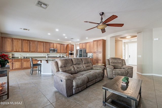 tiled living room featuring ceiling fan and sink