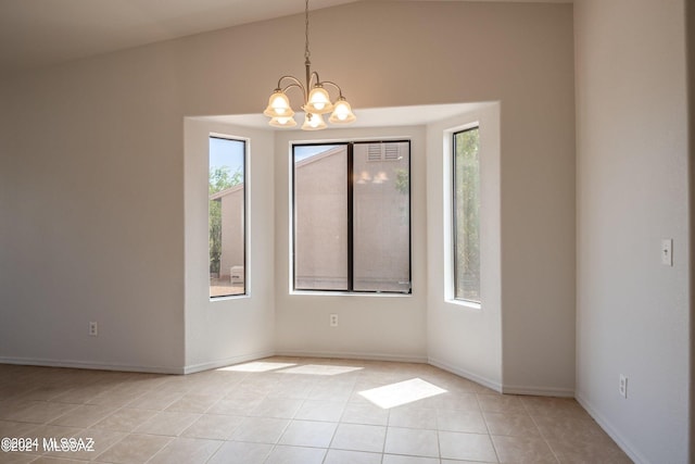 tiled empty room with lofted ceiling and a notable chandelier