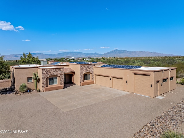 view of front of property featuring a mountain view, solar panels, and a garage