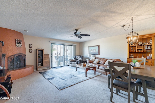 living room featuring ceiling fan with notable chandelier, carpet, and a textured ceiling