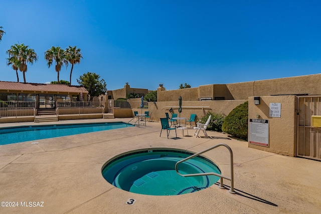 view of swimming pool featuring a community hot tub and a patio