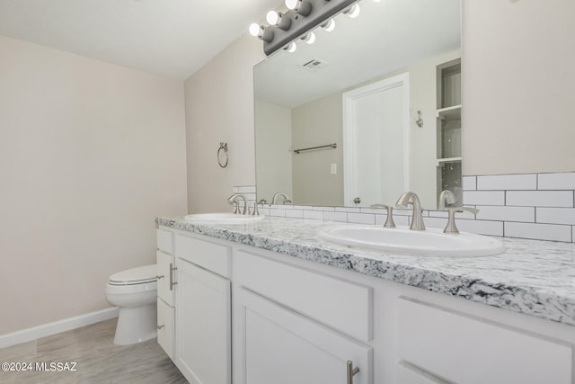 bathroom with vanity, decorative backsplash, and toilet