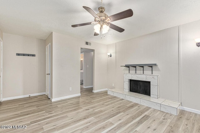 unfurnished living room featuring light hardwood / wood-style floors, a textured ceiling, a fireplace, and ceiling fan