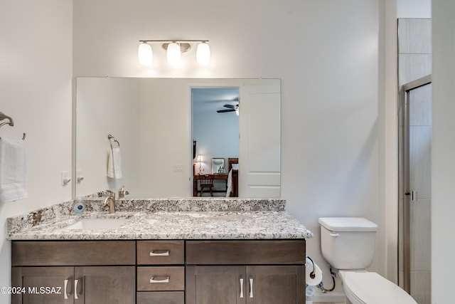 bathroom featuring ceiling fan, vanity, toilet, and an enclosed shower