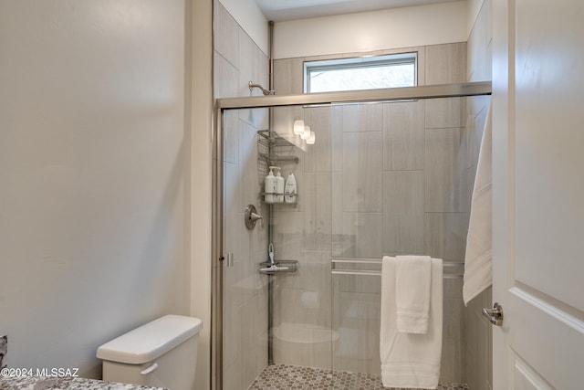 bathroom featuring a shower with door and toilet