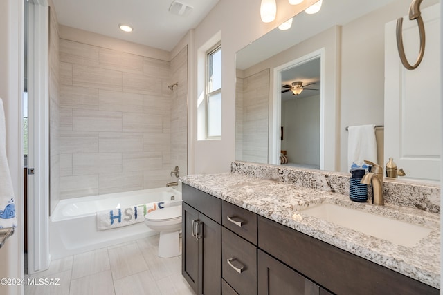 full bathroom with ceiling fan, vanity, toilet, and tiled shower / bath