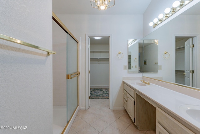 full bathroom with a shower stall, a sink, double vanity, a spacious closet, and tile patterned flooring