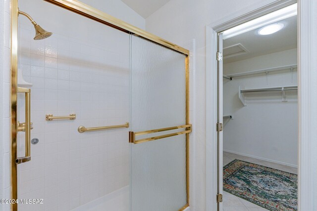 bathroom with a spacious closet, a stall shower, and tile patterned flooring