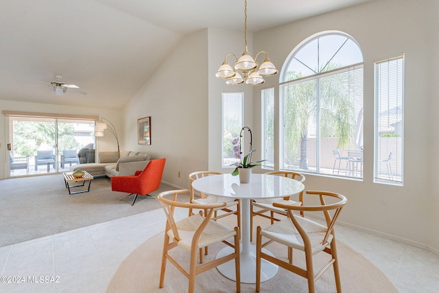 dining room with ceiling fan with notable chandelier, lofted ceiling, and light tile patterned floors