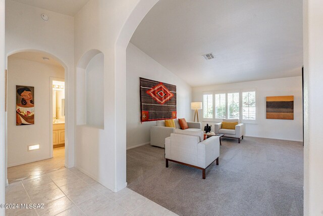 living room with baseboards, visible vents, light carpet, and vaulted ceiling