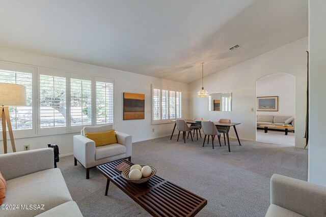 living area with visible vents, vaulted ceiling, light carpet, and baseboards