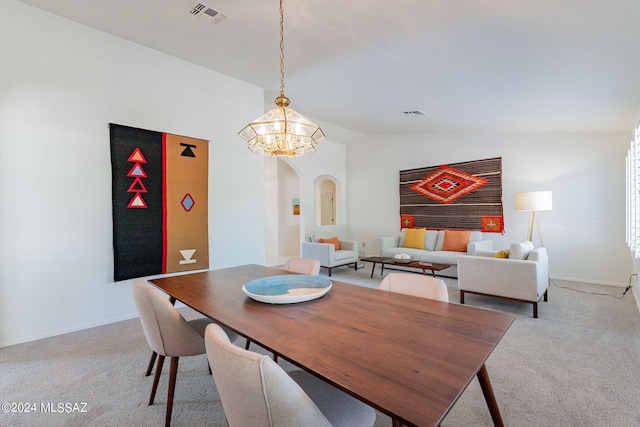 carpeted dining area featuring vaulted ceiling and a chandelier