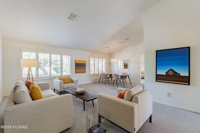 carpeted living room with a notable chandelier, plenty of natural light, and vaulted ceiling