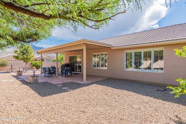 rear view of house featuring a patio, fence, stucco siding, and a tile roof
