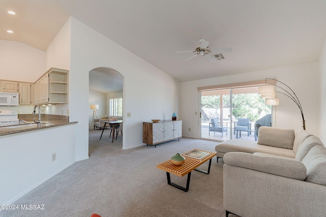 living room with lofted ceiling, ceiling fan, and light carpet