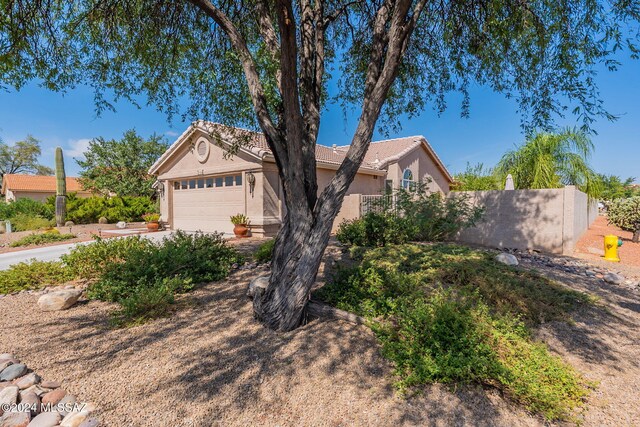 view of front of property featuring stucco siding, a tiled roof, fence, concrete driveway, and an attached garage