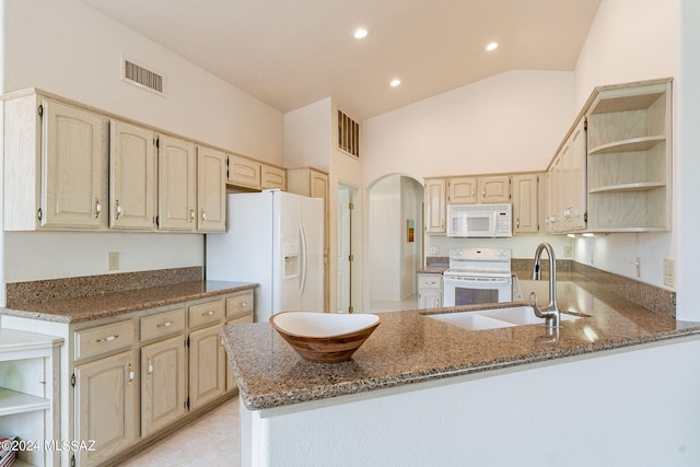 kitchen with stone countertops, white appliances, vaulted ceiling, sink, and kitchen peninsula