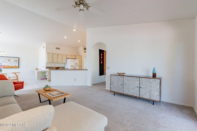 living area featuring arched walkways, ceiling fan, light colored carpet, and vaulted ceiling