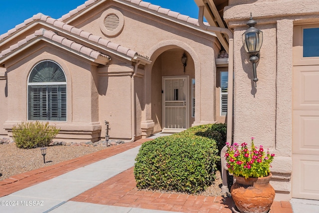 doorway to property featuring stucco siding and a tile roof