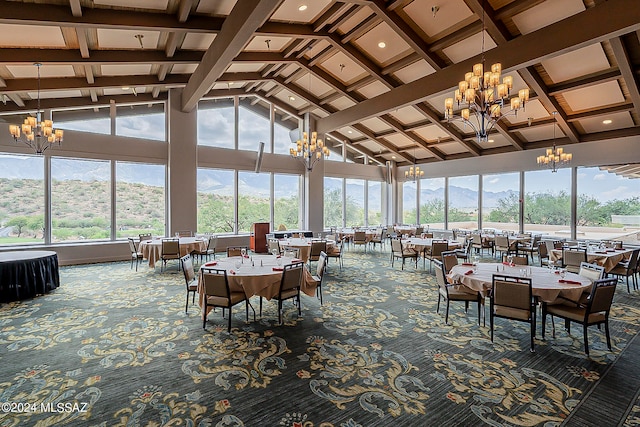 sunroom with a chandelier, lofted ceiling with beams, a mountain view, and a healthy amount of sunlight