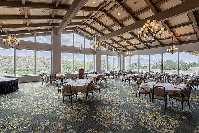 sunroom / solarium with a mountain view, a notable chandelier, and beam ceiling