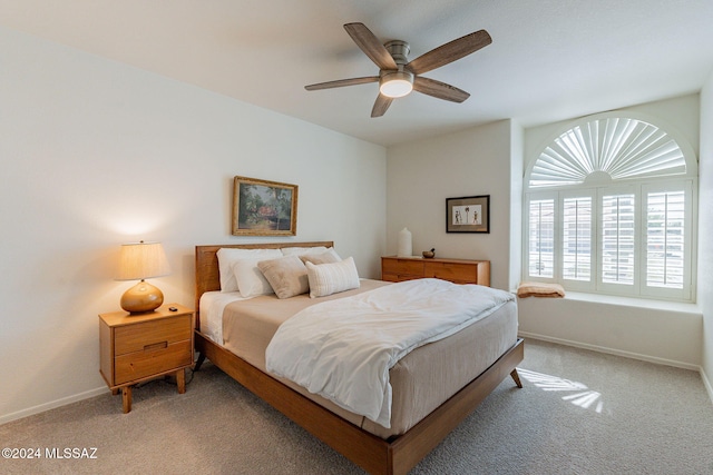 bedroom with a ceiling fan, light carpet, and baseboards