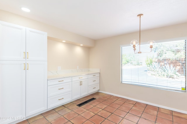 kitchen featuring light tile patterned flooring, pendant lighting, light stone countertops, and white cabinetry