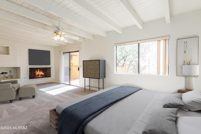 bedroom featuring ceiling fan, beamed ceiling, a fireplace, and light hardwood / wood-style flooring