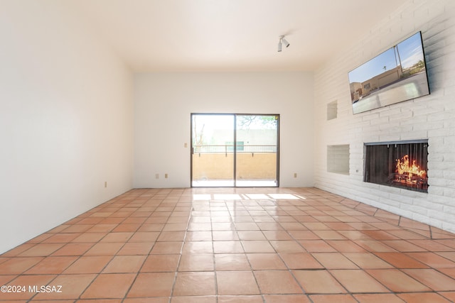 unfurnished living room featuring light tile patterned flooring and a brick fireplace