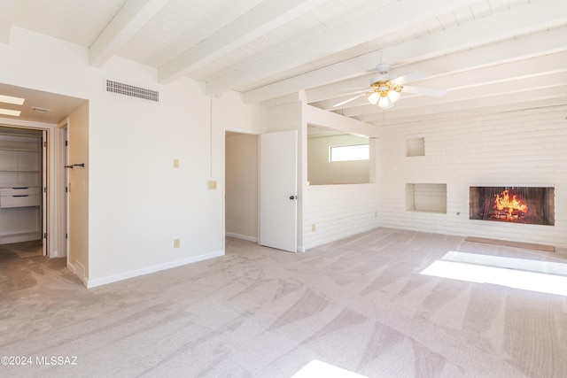 unfurnished living room with light carpet, a fireplace, beam ceiling, and ceiling fan