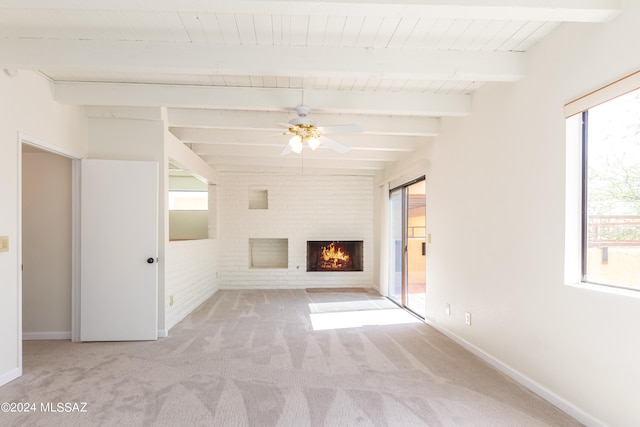 unfurnished living room featuring a brick fireplace, light carpet, beam ceiling, and a healthy amount of sunlight