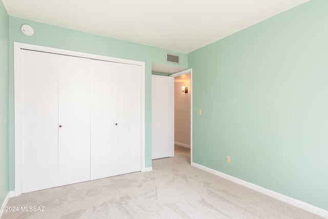 unfurnished bedroom with a closet and light carpet