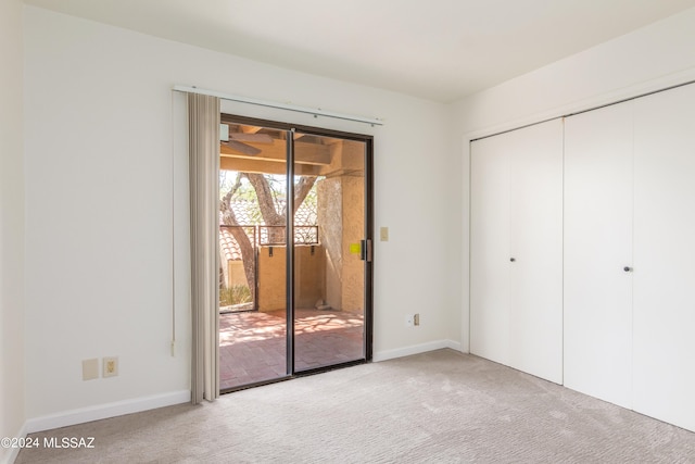 unfurnished bedroom featuring a closet, access to exterior, and light colored carpet