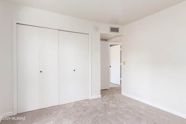 unfurnished bedroom with a closet and light colored carpet