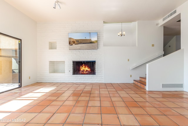 unfurnished living room featuring a fireplace, an inviting chandelier, and light tile patterned floors