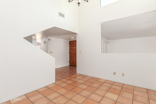 empty room featuring a high ceiling, light tile patterned floors, and a textured ceiling