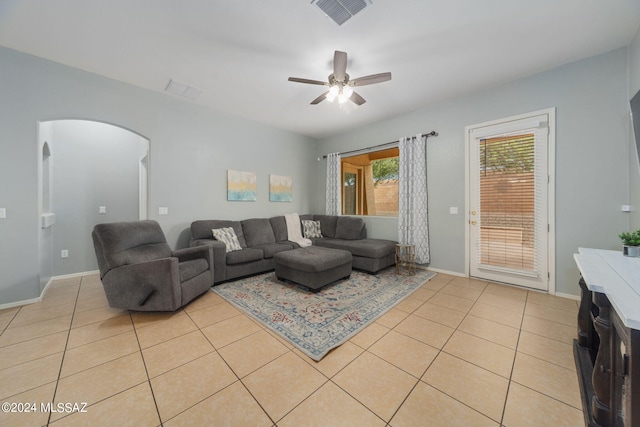living room featuring ceiling fan, visible vents, arched walkways, light tile patterned floors, and baseboards