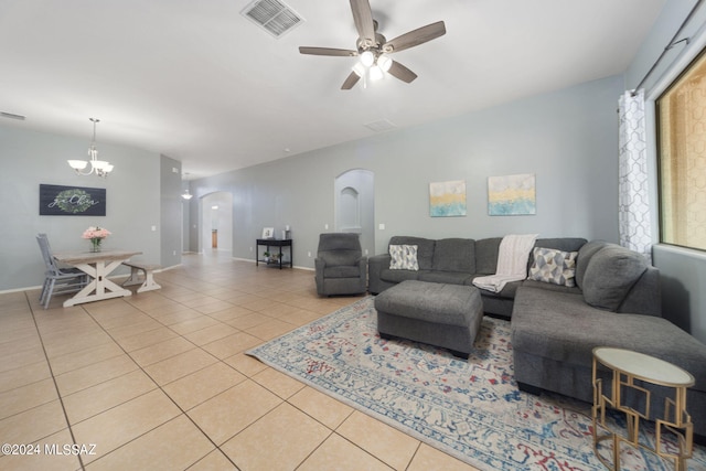 living area with visible vents, baseboards, tile patterned floors, arched walkways, and ceiling fan with notable chandelier