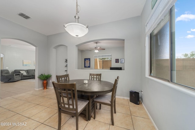 dining room featuring visible vents, light tile patterned flooring, baseboards, ceiling fan, and arched walkways