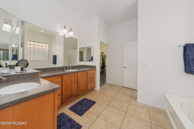 bathroom with tile patterned floors, a spacious closet, a tub to relax in, and vanity