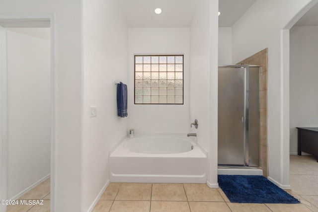 bathroom featuring tile patterned floors, a bath, and a stall shower